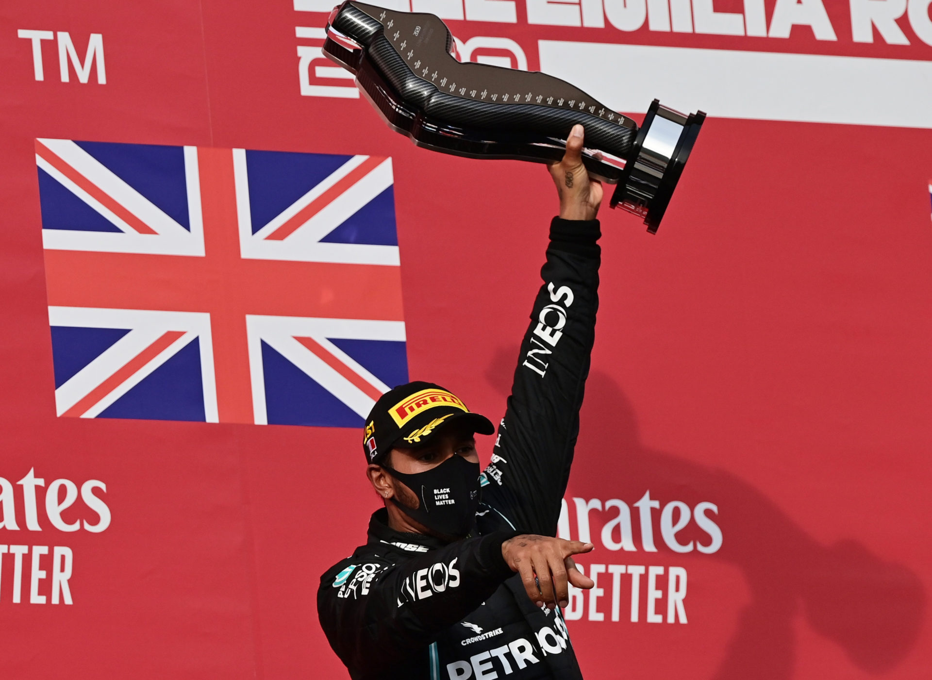 Formula One, F1- Lewis Hamilton holding his trophy high. He races under the flag of the UK.