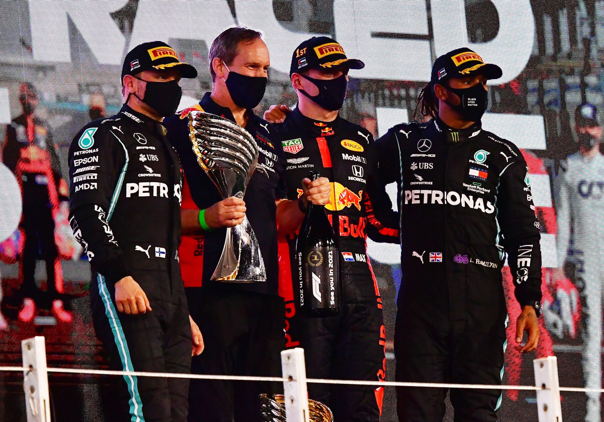 F1 racers, Max Verstappen, Valtteri Bottas, and Lewis Hamilton on the podium. Every racer losing weight after the race.