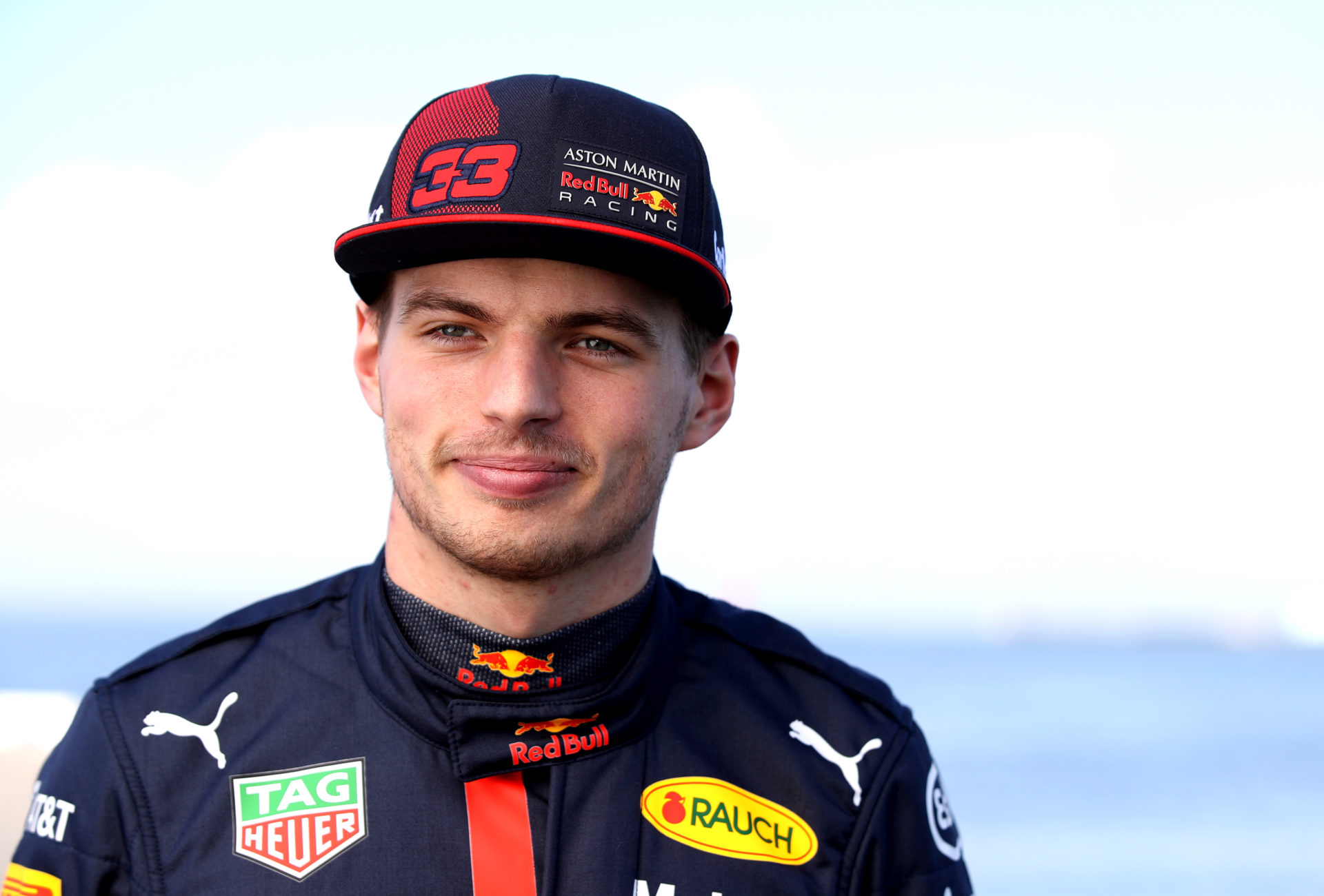 Max Verstappen wears a smile as he looks on in his Red Bull racing suit