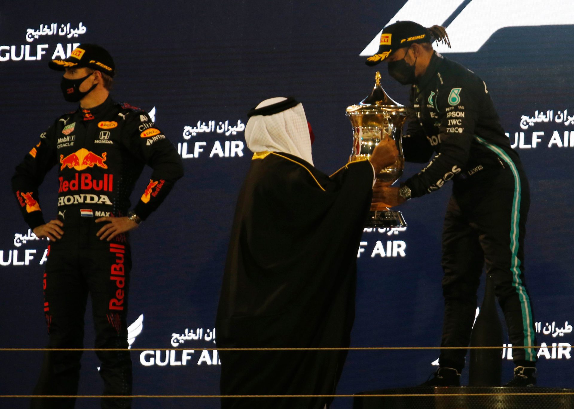 Lewis Hamilton is presented with the trophy for winning the race as Max Verstappen looks on